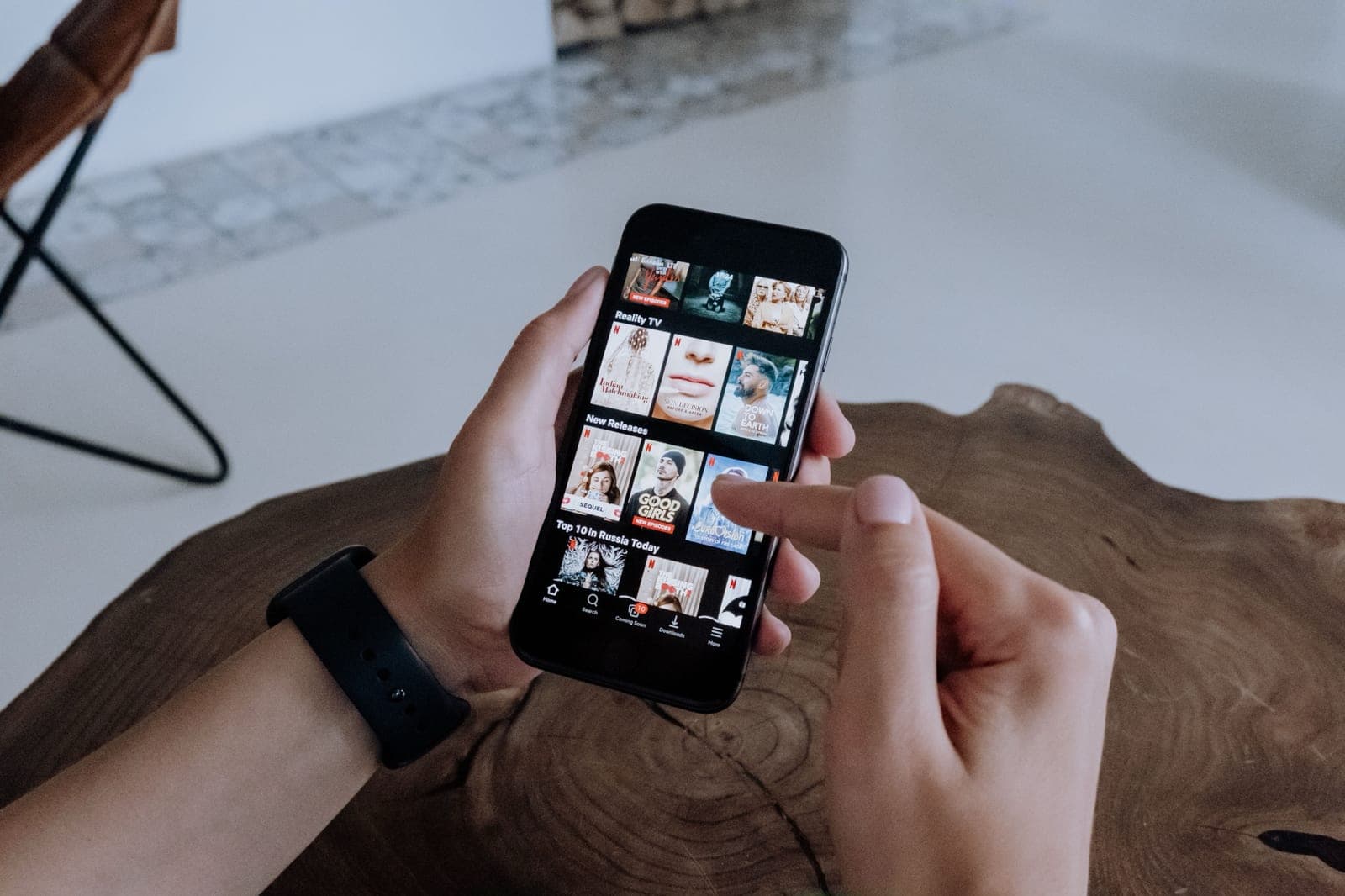 Des mains tenant un téléphone ouvert sur le catalogue d’une application de diffusion